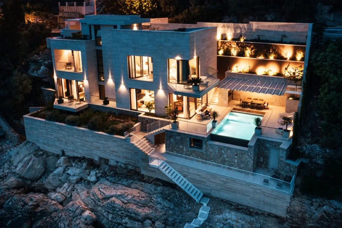 Villa Anthon illuminated at night above the sea, aerial view