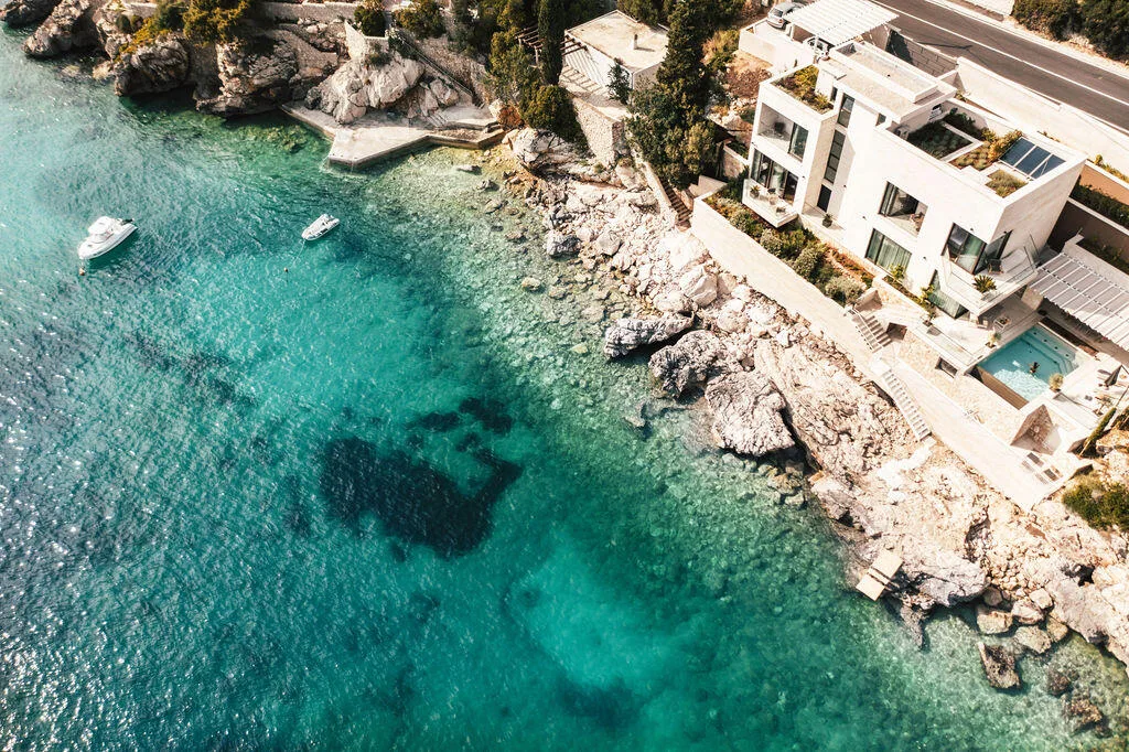 Aerial view of Villa Anthon on the rocky shore above turquoise water, Štikovica