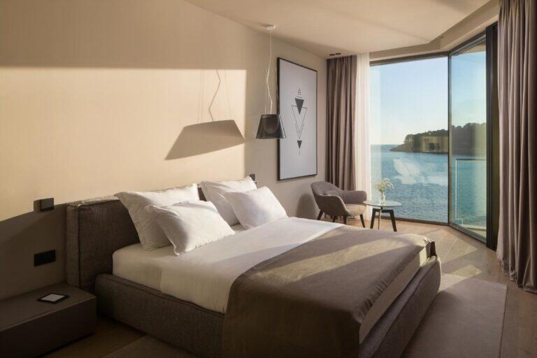 Schlafzimmer mit Kingsize-Bett und Eckfenster mit Meerblick in der Villa Anthon