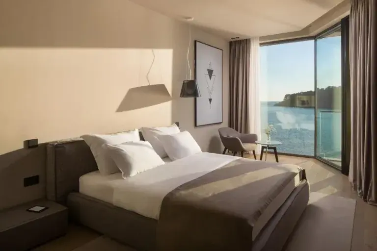 Bedroom with king-size bed and corner sea-view windows at Villa Anthon