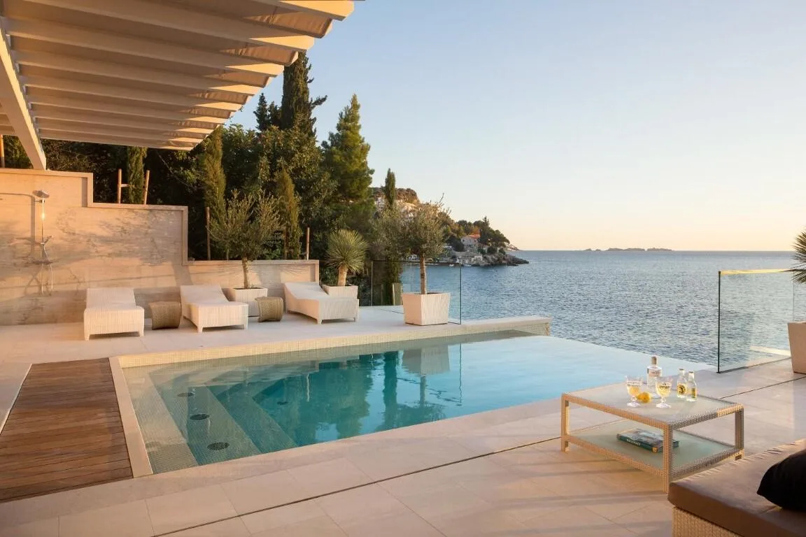 Infinity pool and sun loungers overlooking the sea at sunset at Villa Anthon