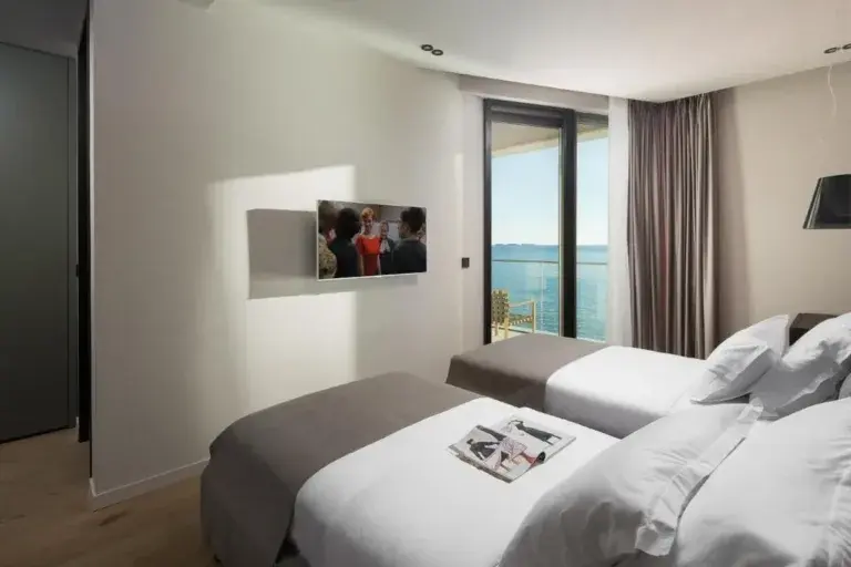Twin bedroom with two beds and sea-view window at Villa Anthon