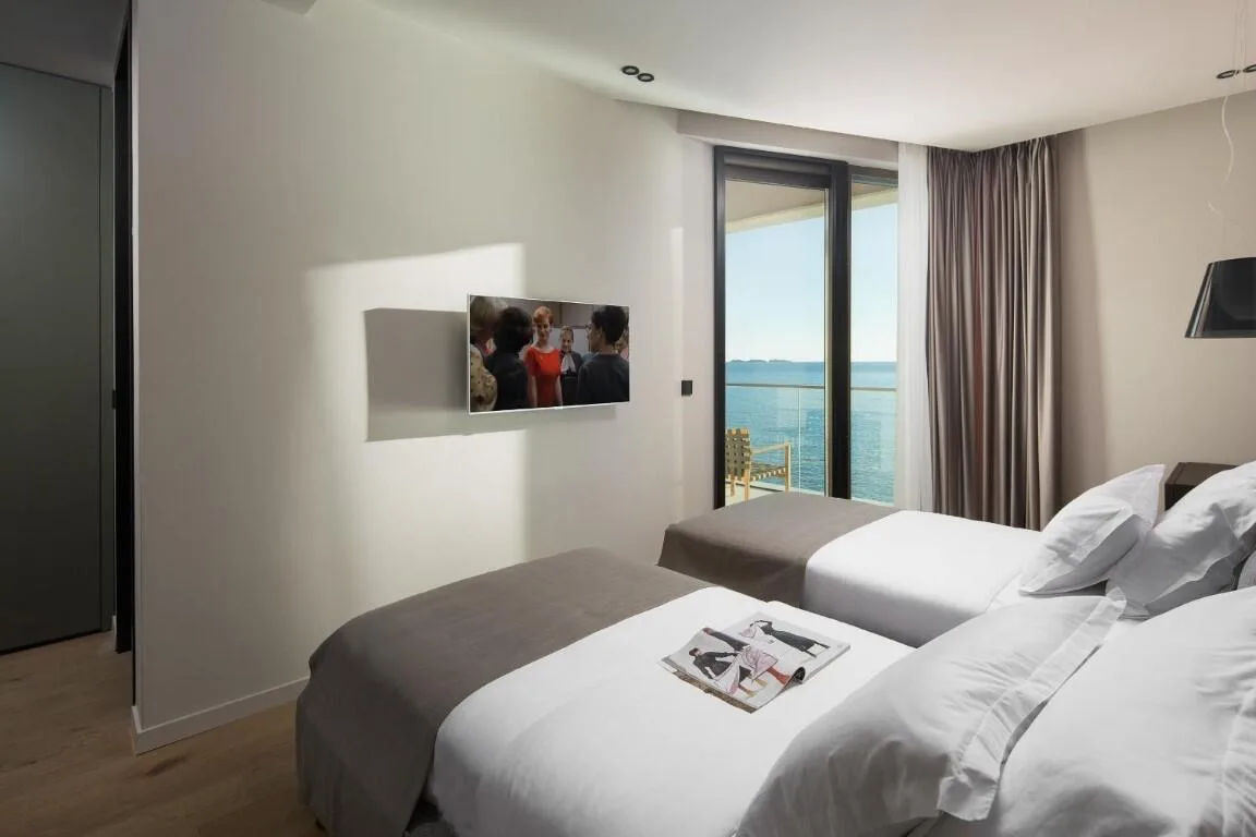 Twin bedroom with two beds and sea-view window at Villa Anthon