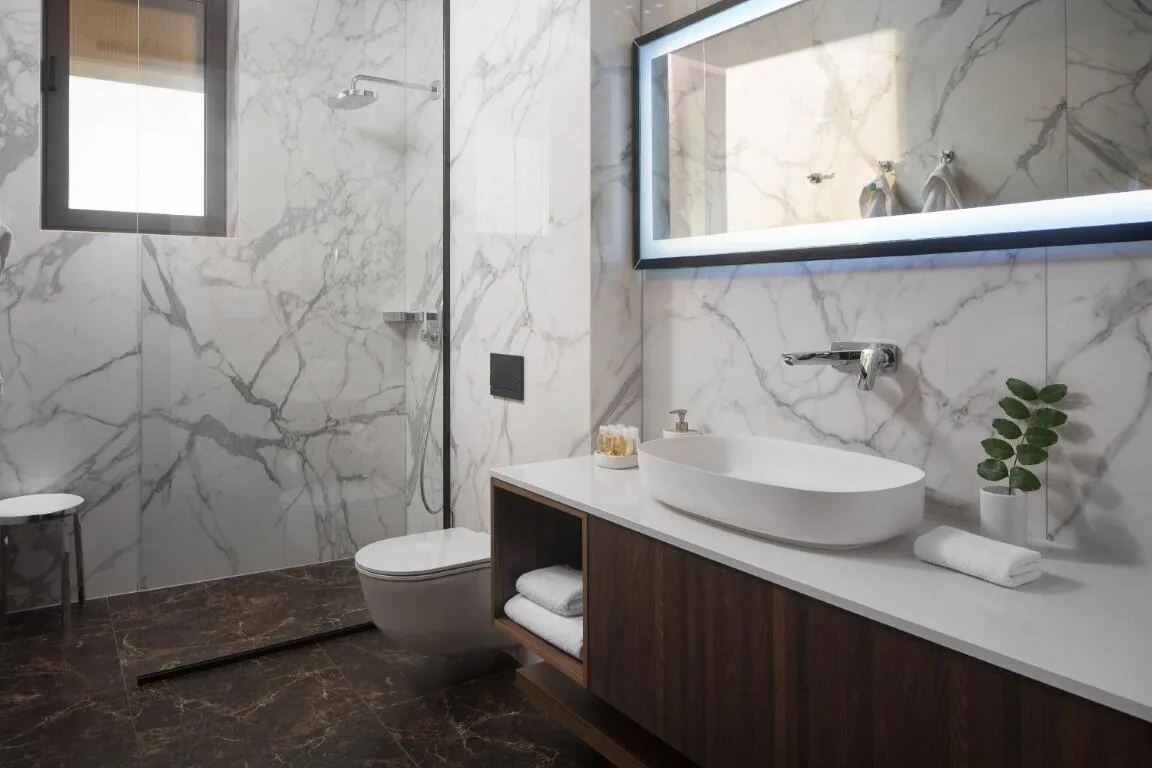 Marble bathroom with vessel basin and backlit mirror at Villa Anthon