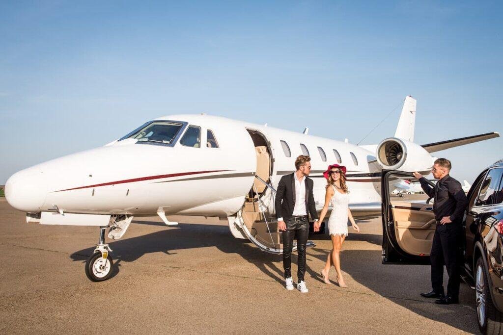 Well-dressed couple holding hands as they walk away from a private jet on the airport apron