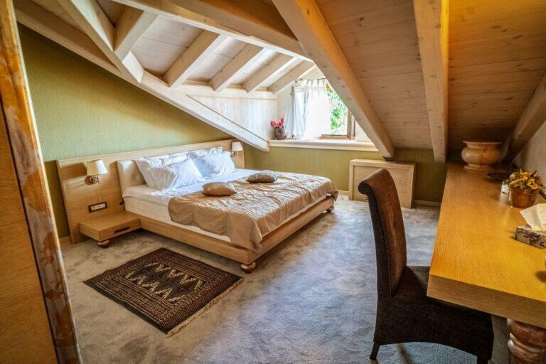 Attika-Schlafzimmer mit Kingsize-Bett und Holzbalken in der Villa Revelin