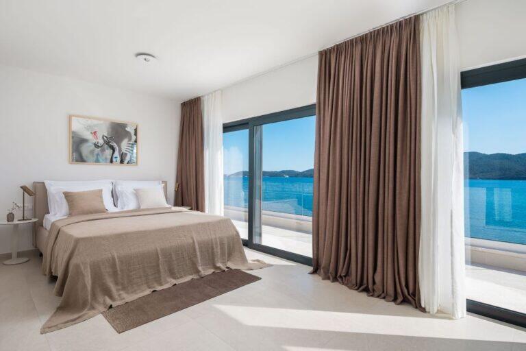 Schlafzimmer mit Kingsize-Bett und Fenstern mit Meerblick in der Villa Maris