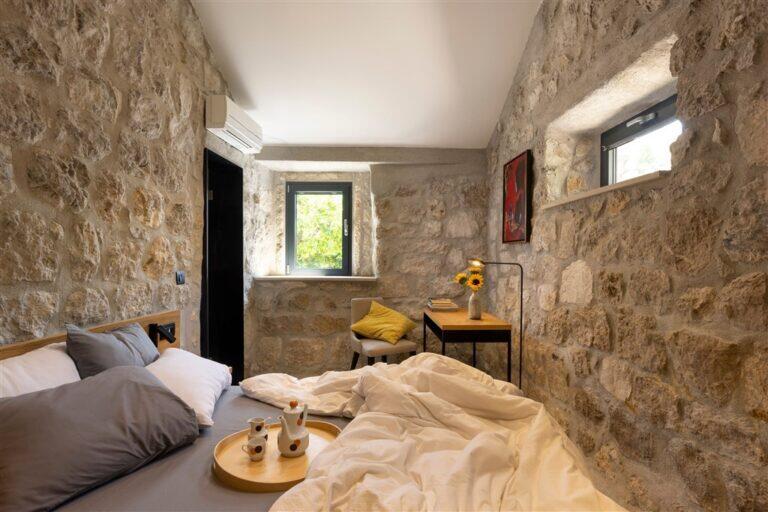 Schlafzimmer mit Kingsize-Bett und Steinwänden in der Villa MaR
