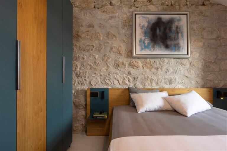 Schlafzimmer mit Kingsize-Bett und Steinmauer in der Villa MaR