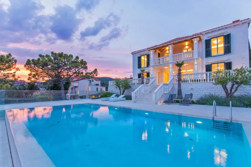 Classic white villa and pool under a pink sky at Villa Vintage