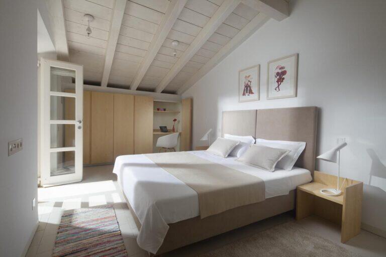 Attik-Schlafzimmer mit Kingsize-Bett unter weißen Balken in der Villa Oasis