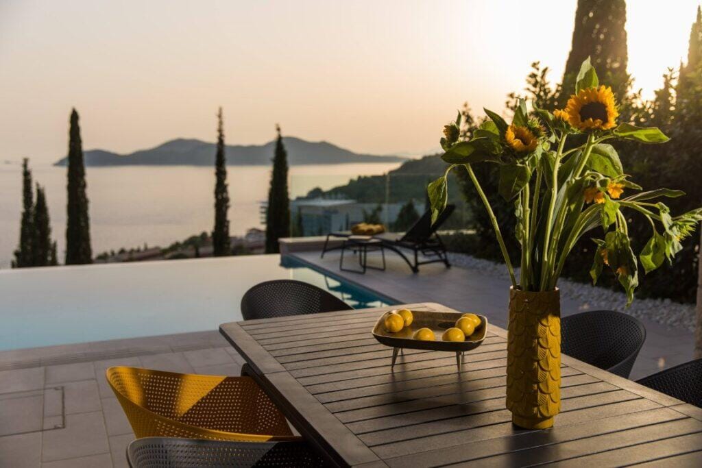 Terrassenstühle mit Sonnenblumen und einem Infinity-Pool mit Blick auf die Elafiti-Inseln bei Sonnenuntergang, Villa Helia