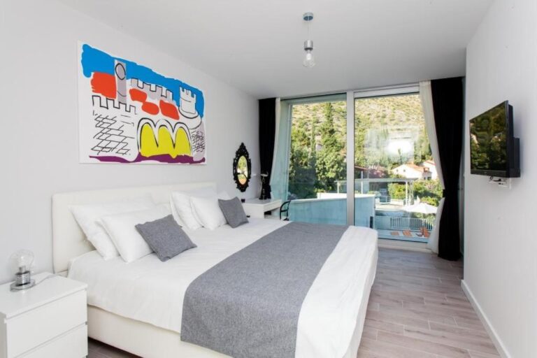 Schlafzimmer mit Kingsize-Bett und farbenfrohen Kunstwerken in der Villa Art