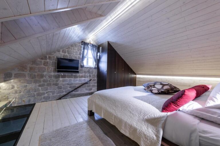 Attic-Schlafzimmer mit Kingsize-Bett und Steinmauer in der Villa Carpe Diem