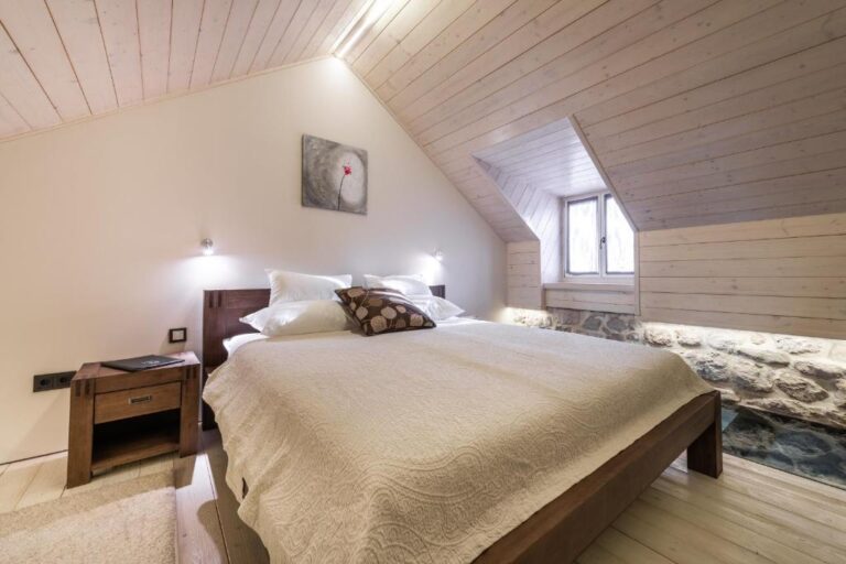 Schlafzimmer mit Kingsize-Bett unter einem schräg abfallenden Decken in der Villa Carpe Diem