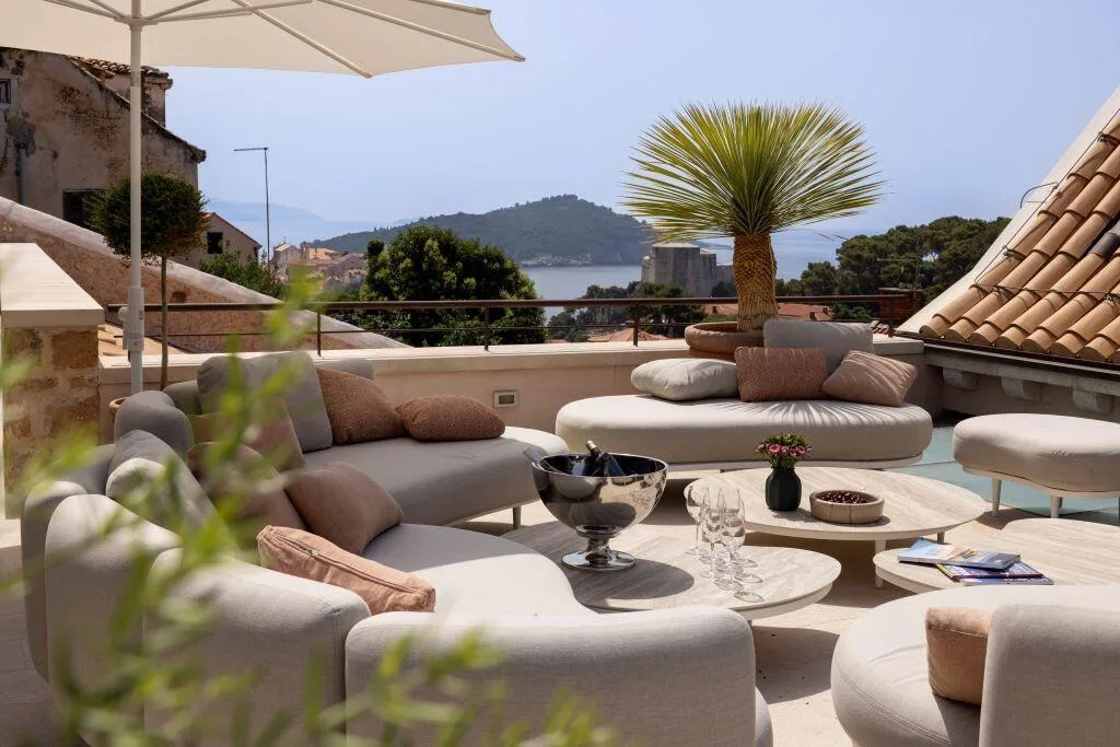 Outdoor lounge with palm and sea views on the terrace at Villa La Rose