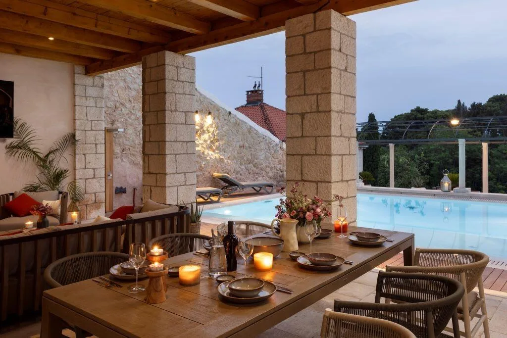 Outdoor dining table with candles beside the pool at Villa La Rose