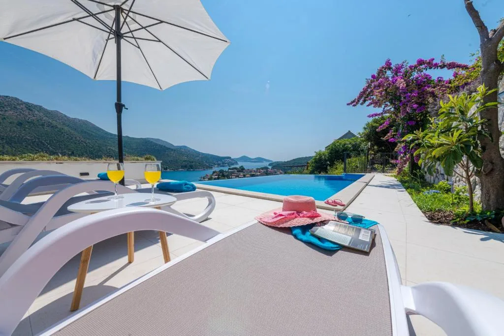 Chaises longues avec serviettes et bougainvilliers près de la piscine à House Maure