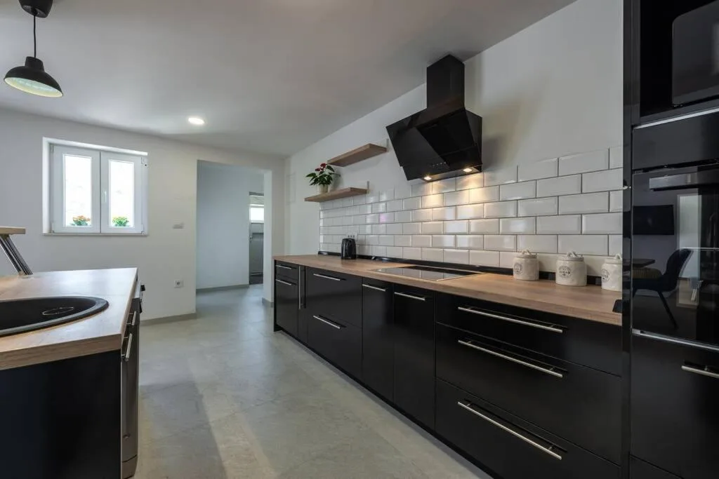 Cuisine moderne noire avec des carreaux blancs chez House Maure