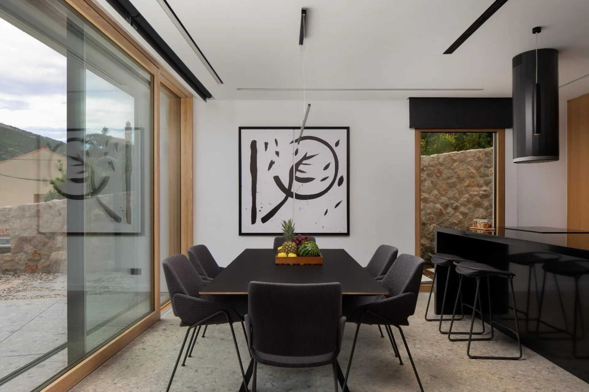 Dining table with black chairs and abstract artwork at Villa Palazzo