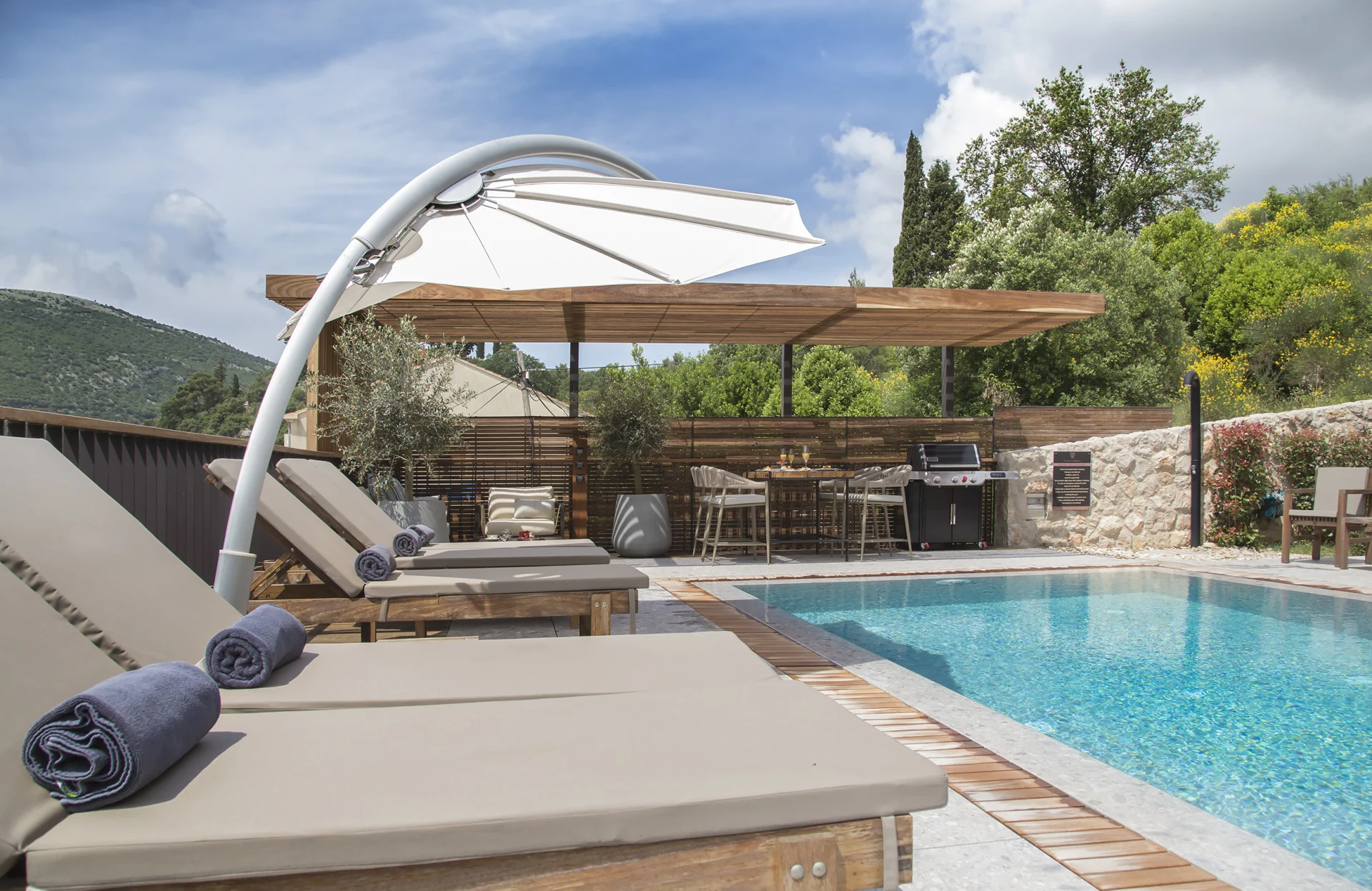 Sun loungers with towels and parasol beside the pool at Villa Palazzo