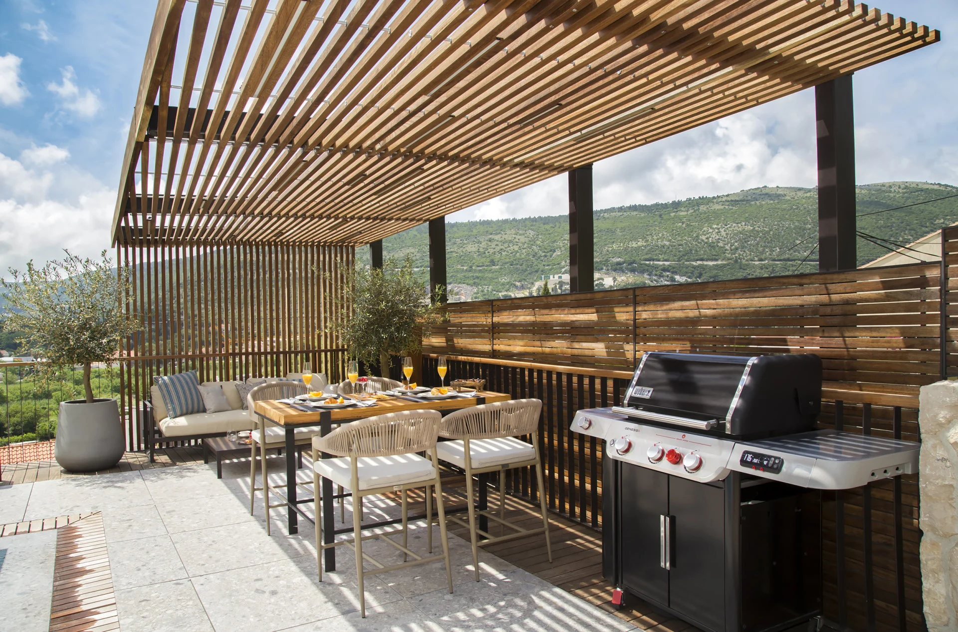 Outdoor kitchen with barbecue and dining under a pergola at Villa Palazzo