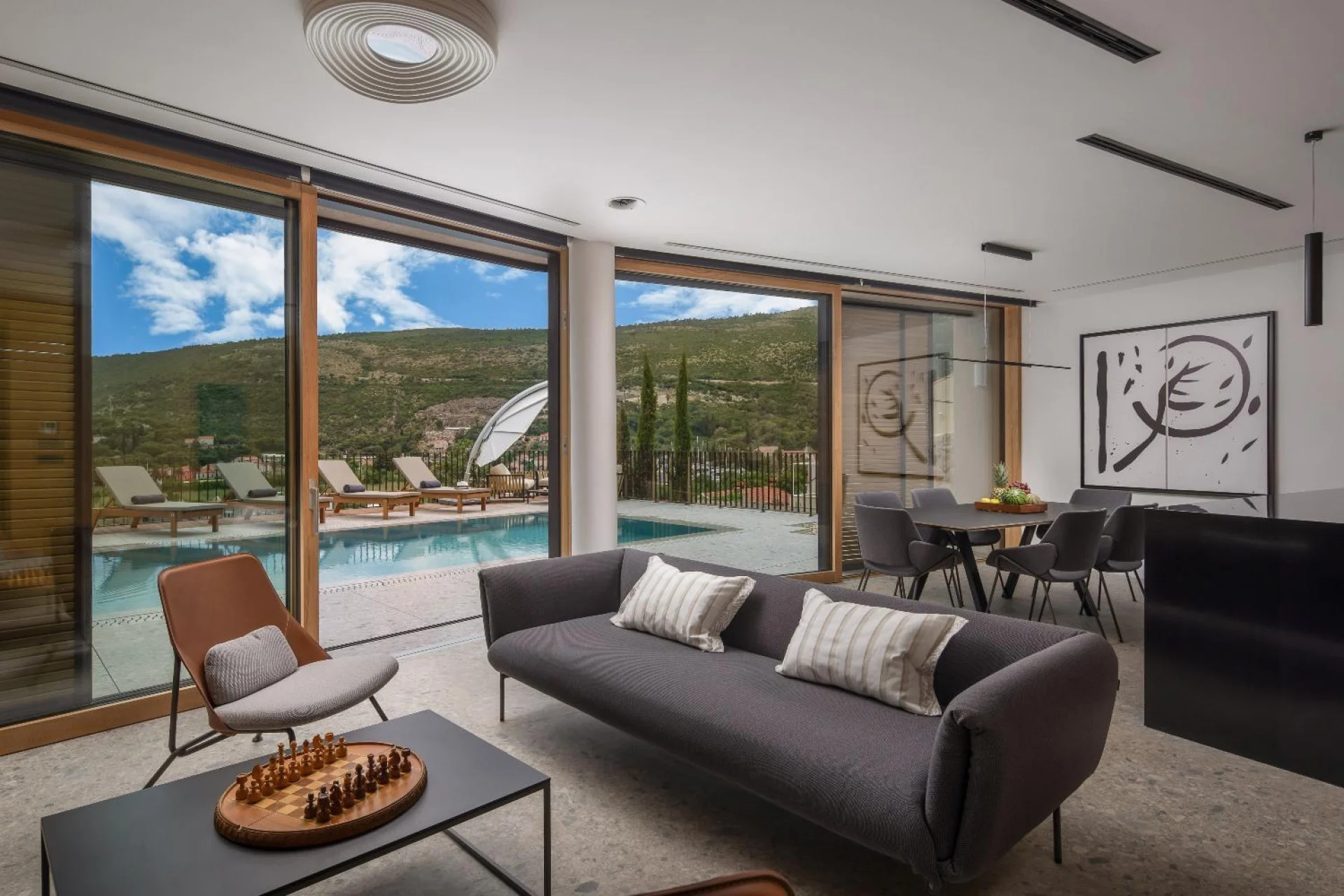Living room with grey sofa and pool view at Villa Palazzo