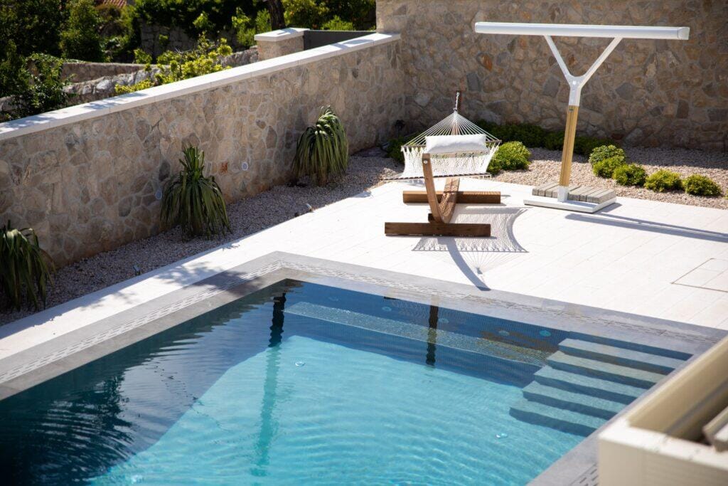 Poolstufen und Liegestühle auf der Steinterrasse von Villa Auna