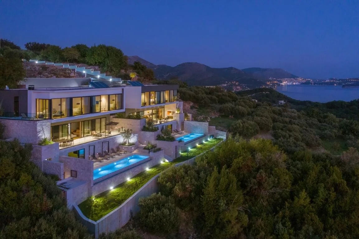 Aerial view of Villa Elena with illuminated infinity pools at dusk above Orašac