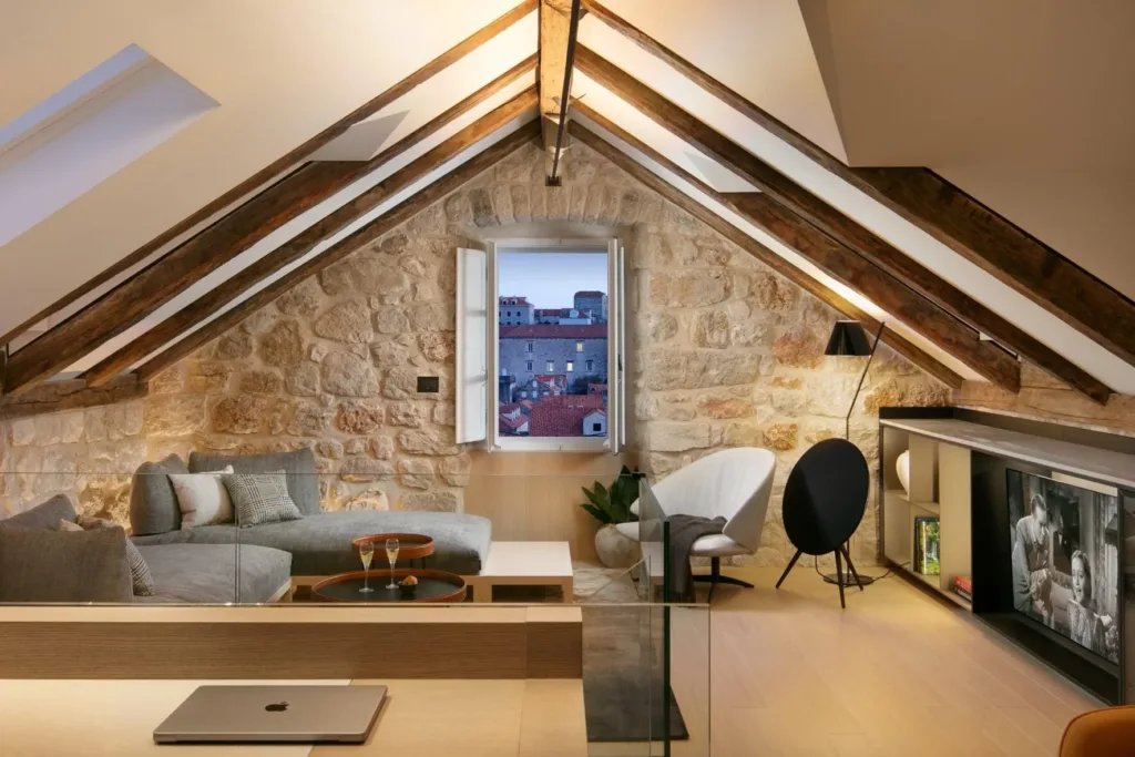 Attic living room with stone walls and window onto Dubrovnik Old Town rooftops at Villa Lapisa