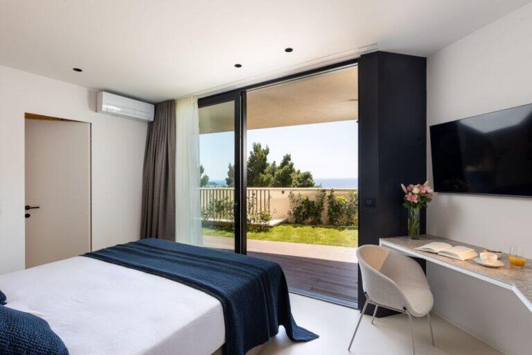 Schlafzimmer mit Kingsize-Bett, Schreibtisch und Gartenblick in der Villa Amari Monte