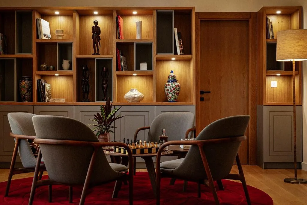 Reading area with armchairs and lit shelves at Villa La Rose