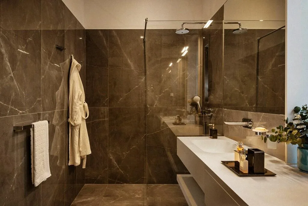 Bathroom with dark marble walls and rain shower at Villa La Rose