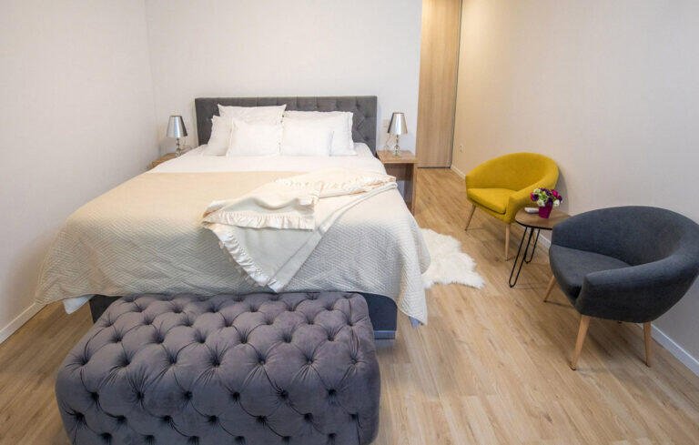 Bedroom with king-size bed and tufted ottoman at Villa Aether