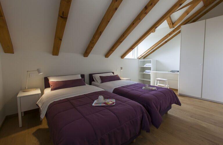 Schlafzimmer mit zwei Einzelbetten unter Holzbalken in der Villa Ella