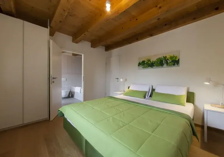 Bedroom with king-size bed and green bedding at Villa Ella