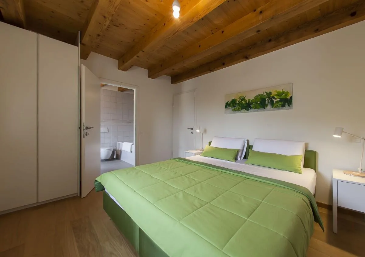 Bedroom with king-size bed and green bedding at Villa Ella