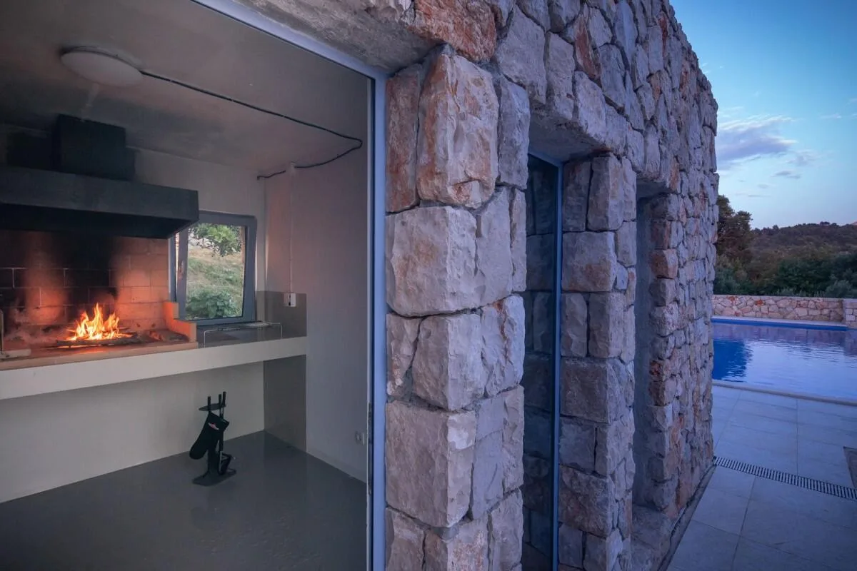 Outdoor fireplace and barbecue in a stone wall at Villa Ella