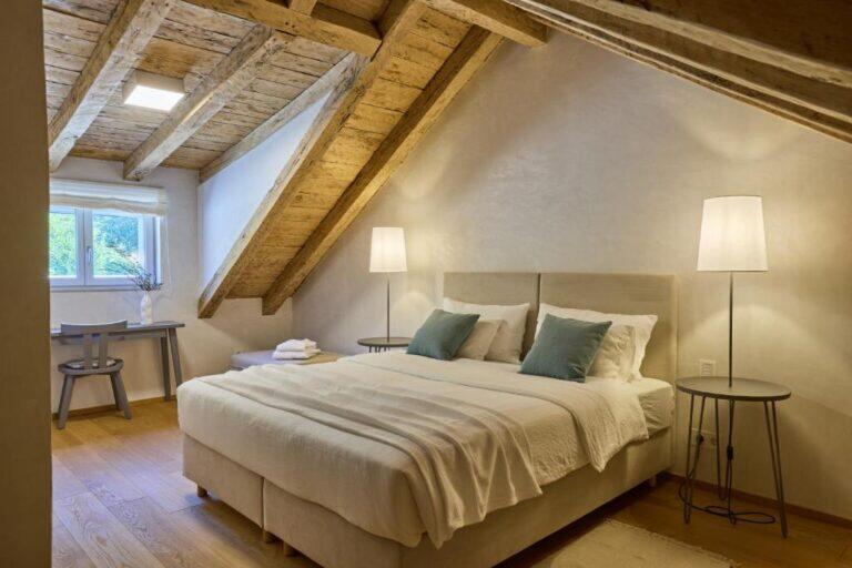 Attika-Schlafzimmer mit Kingsize-Bett unter Holzbalken in der Villa Ghetaldi 1516