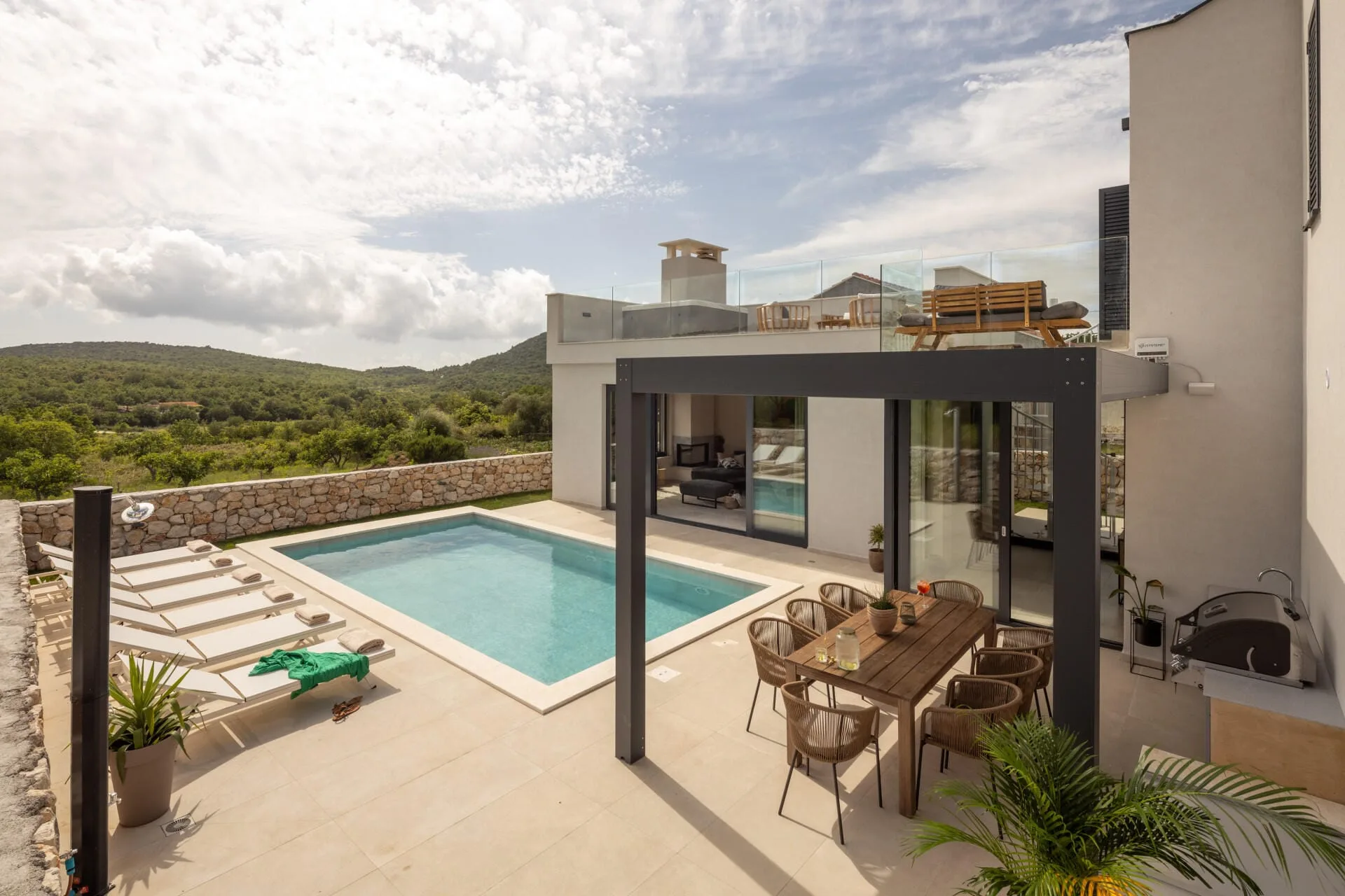 Pool terrace with pergola dining area and sun loungers at Villa Petra