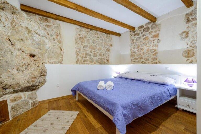 Bedroom with queen-size bed and stone wall at Villa Zeus