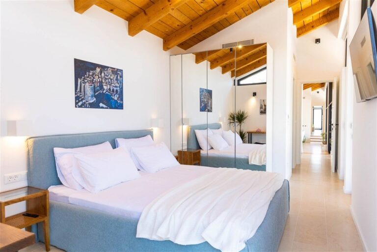 Schlafzimmer mit Kingsize-Bett und blauer Kopfteil an der Villa Moa