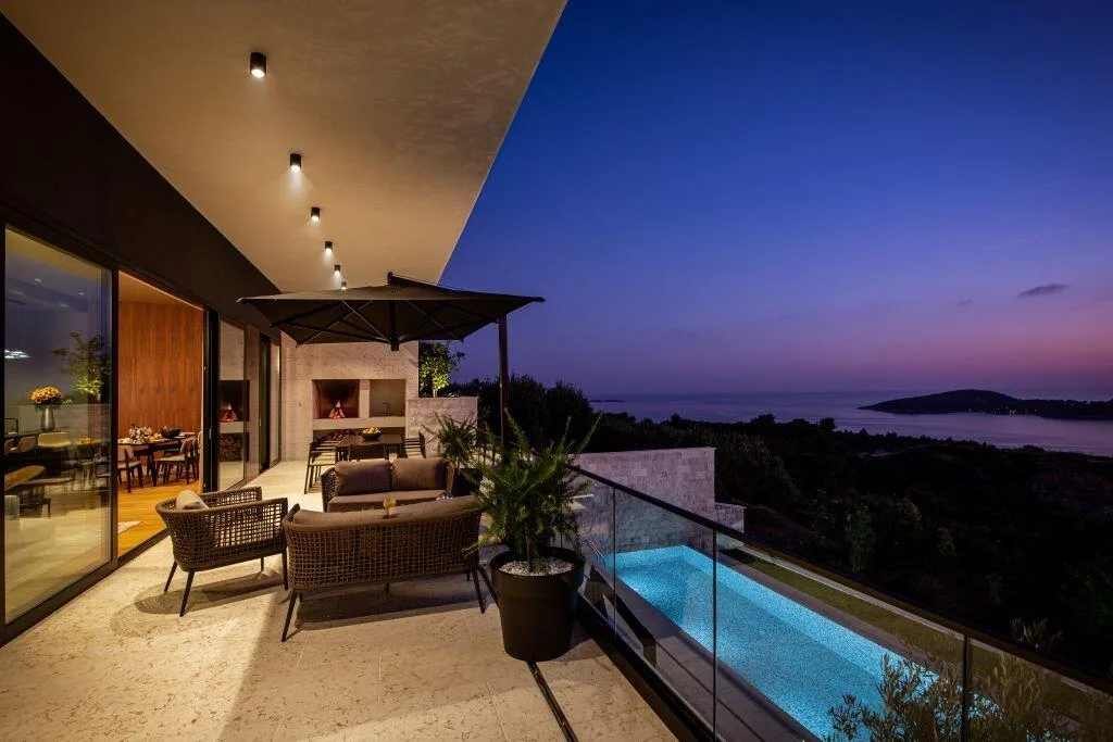 Outdoor lounge and pool lit at twilight at Villa La Frida