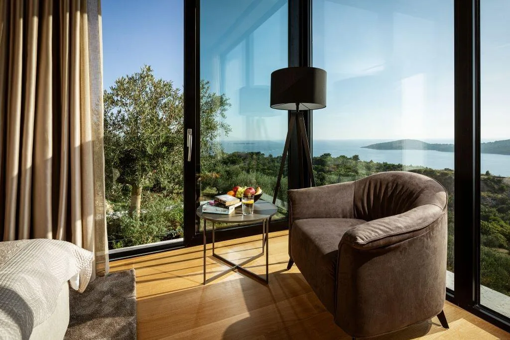 Armchair beside floor-to-ceiling windows with sea view at Villa La Frida
