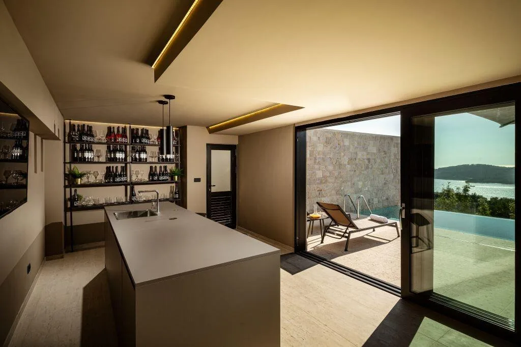 Kitchen island and wine shelves opening onto the pool at Villa La Frida