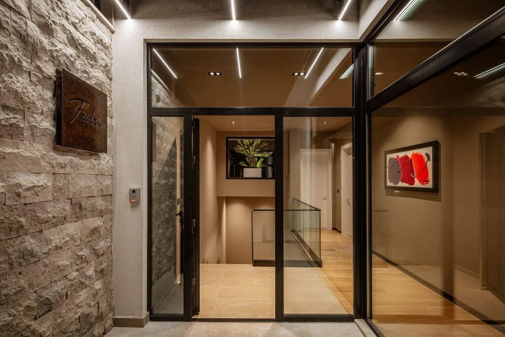 Entrance with stone wall and glass doors at Villa La Frida