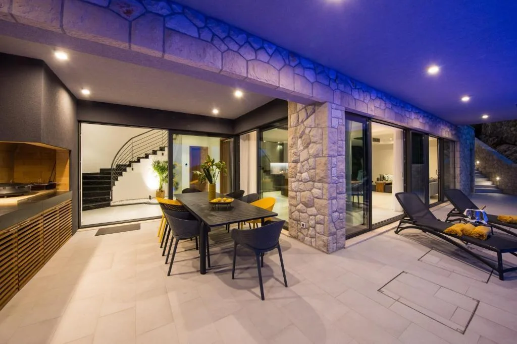 Outdoor kitchen and dining terrace lit at night at Villa Helia