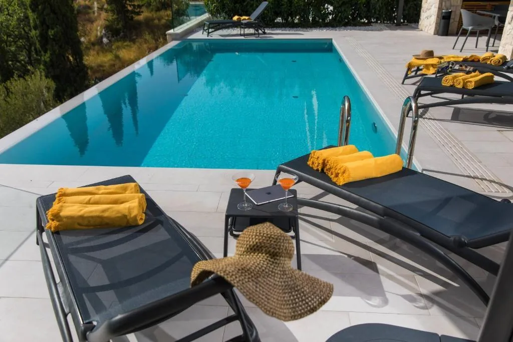 Sun loungers with yellow towels beside the pool at Villa Helia