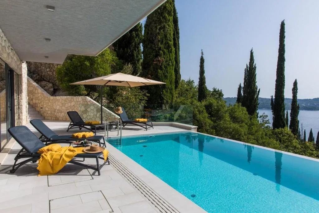 Infinity pool and sun loungers with cypresses at Villa Helia