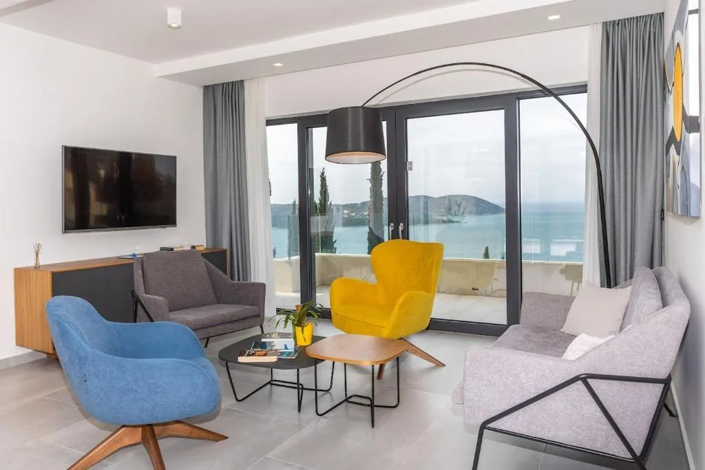 Lounge with yellow and blue armchairs facing the sea at Villa Helia